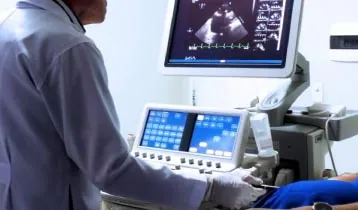 Médico operando o aparelho de ecocardiograma, com a imagem do coração no monitor