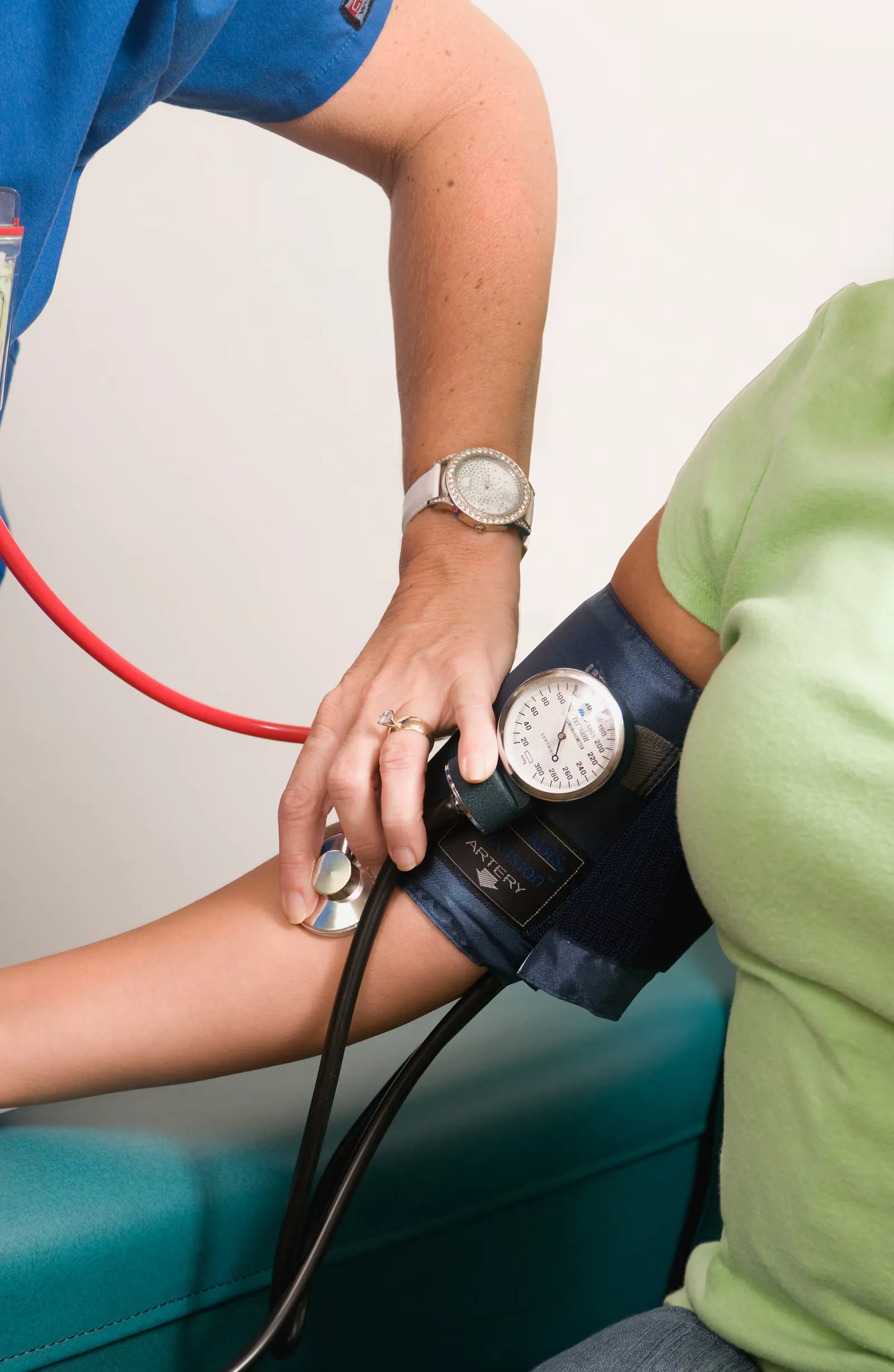 Profissional ajustando o manguito do medidor de pressão no braço de uma paciente