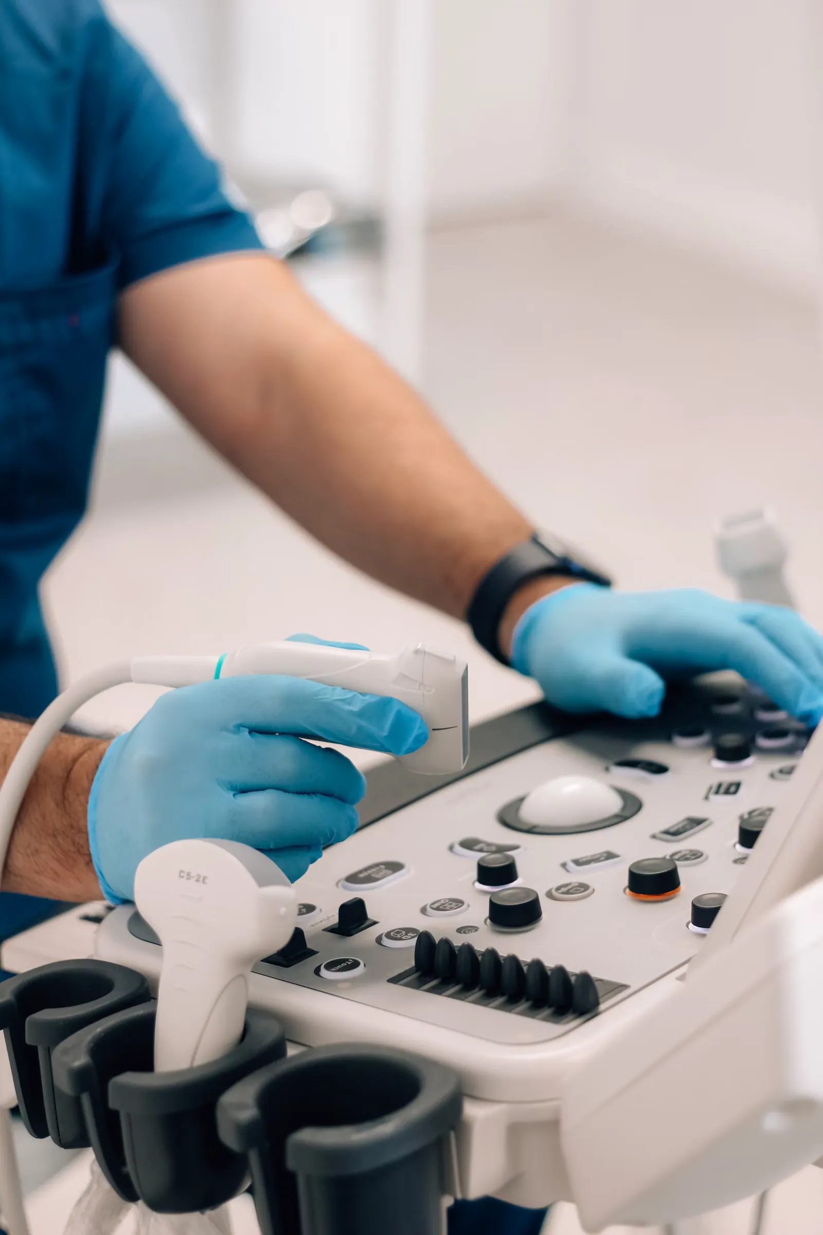 Profissional de luvas segurando o transdutor do aparelho de ecocardiograma